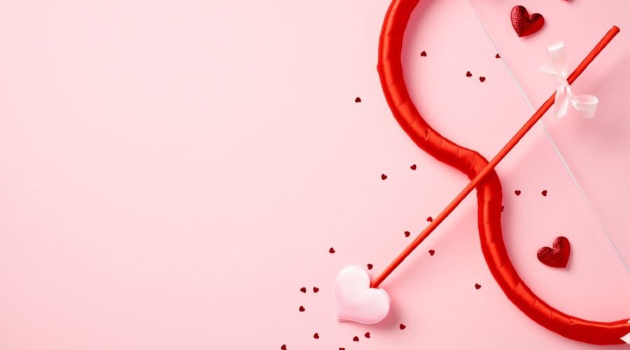 cupid bow and arrow, hearts, confetti on pink background_shutterstock_2555474021 900x500